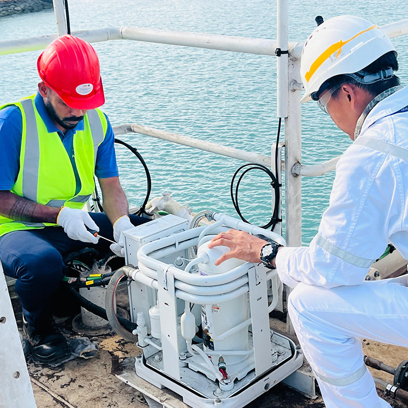 Two men are performing maintenance on an air conditioning unit