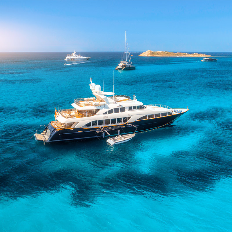 A large yacht is moored near an island