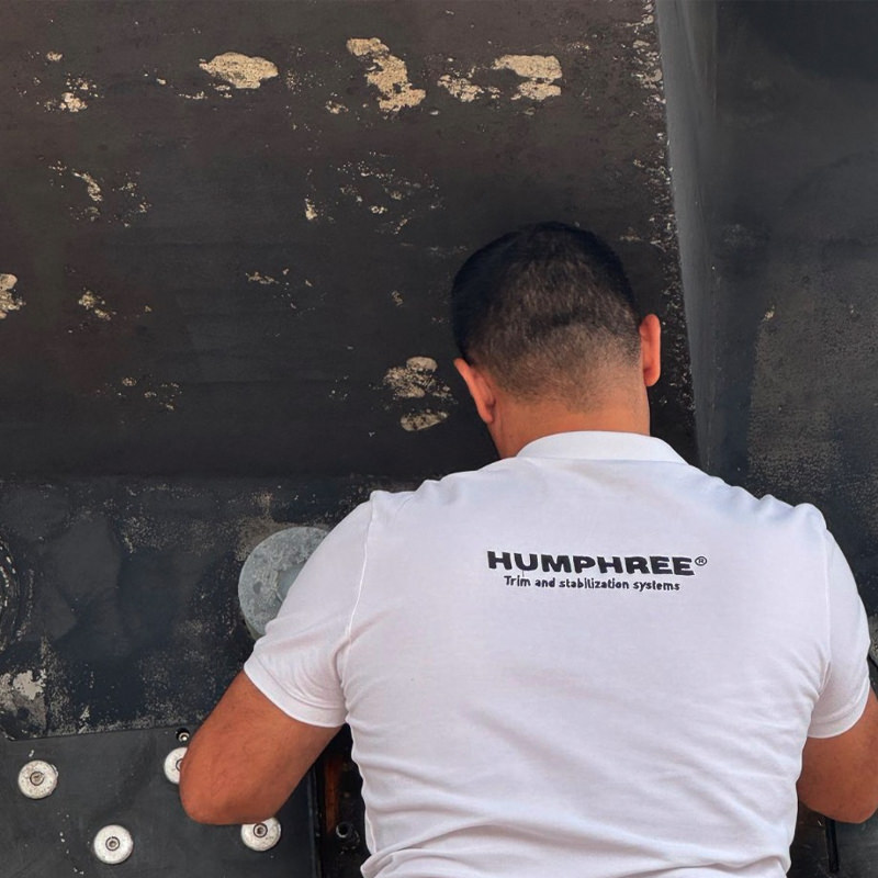 A man is working on the side of a large marine vessel